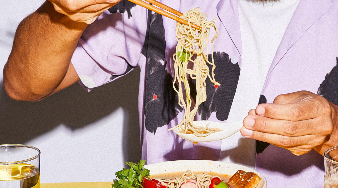 Scooping IMMI Ramen noodles with chopsticks above a bowl of healthy IMMI Ramen noodles. 